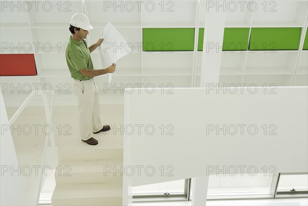 Male architect looking at plan in recently finished office building