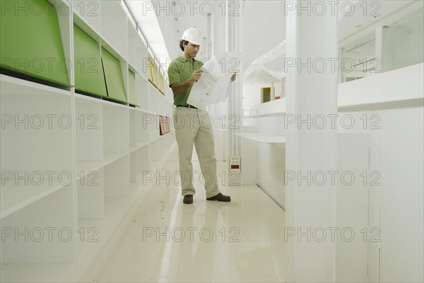 Male architect looking at plan in recently finished office building