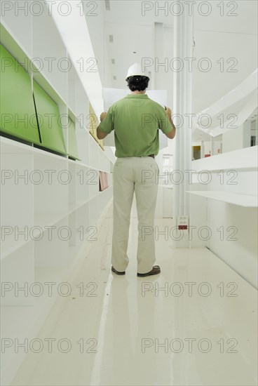 Male architect looking at plan in recently finished office building