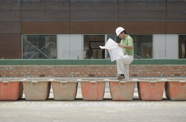 Engineer studying plan on construction site smiling profile