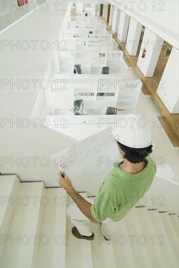 Man wearing hard hat standing in new office holding plans