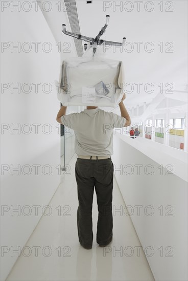 Man carrying chair thorugh office rear view