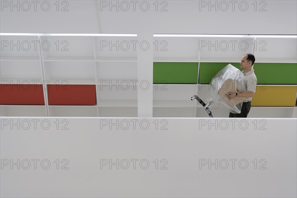 Male office worker carrying new chair wrapped in plastic sheet