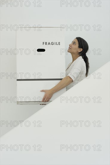 Woman carrying boxes downstairs side view