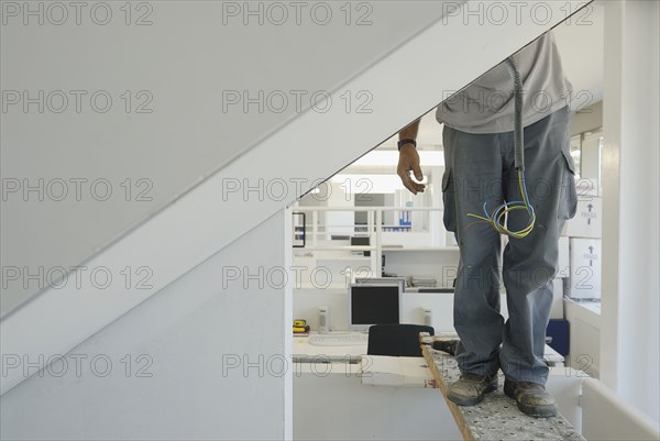 Workman installing electric cabling in new office low section