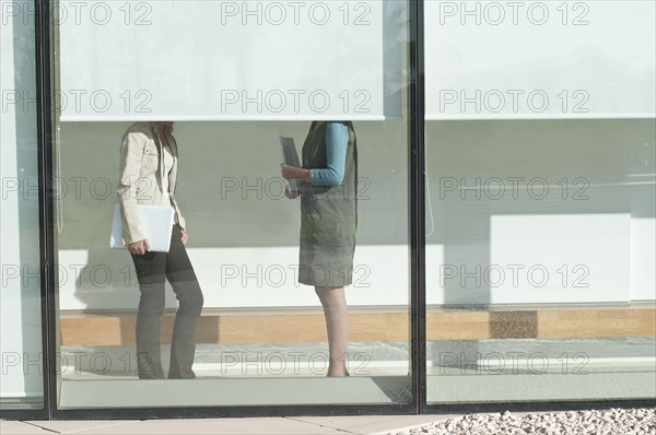 two women talking partly hidden behind screen