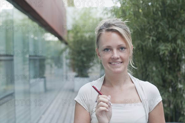 young woman hlding pen looking to camera