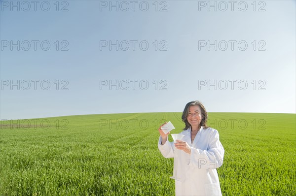 female scientist with test tube in green field