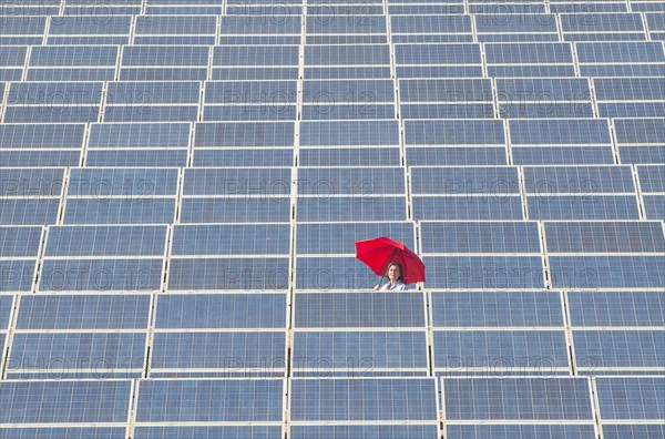 woman holding red umbrella in solar power plant