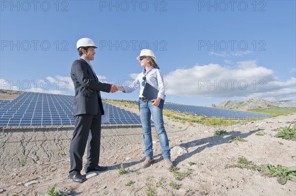 businessman shaking engineer's hand in solar plant