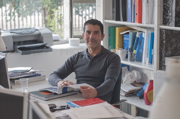 office worker sitting at desk smiling to camera