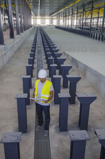 Worker reading blueprints in warehouse