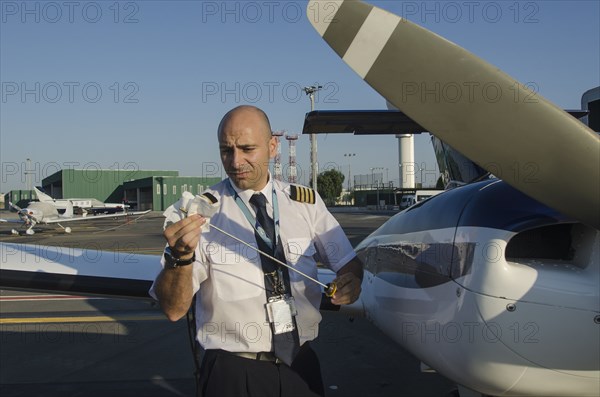 Pilot checking oil in airplane