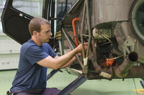 Hispanic mechanic working on helicopter in hangar