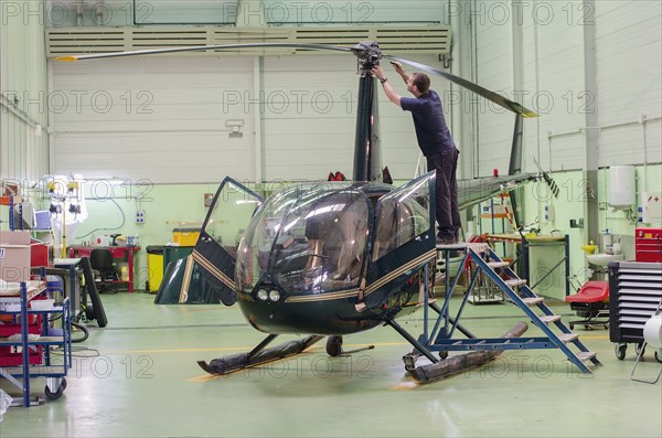 Hispanic mechanic working on helicopter in hangar