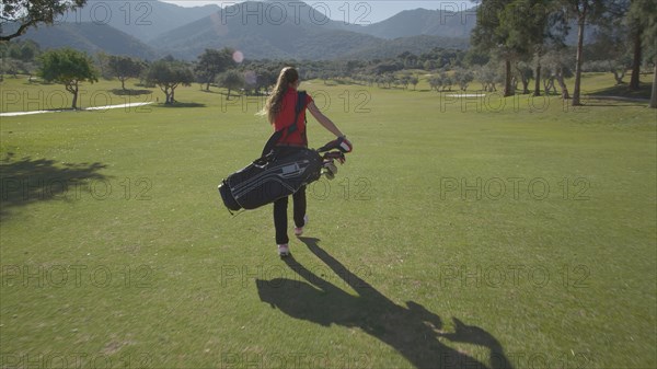 Caucasian woman carrying golf bag on course