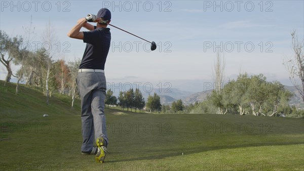 Caucasian man teeing off on golf course