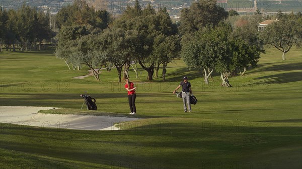 Caucasian couple playing golf on course