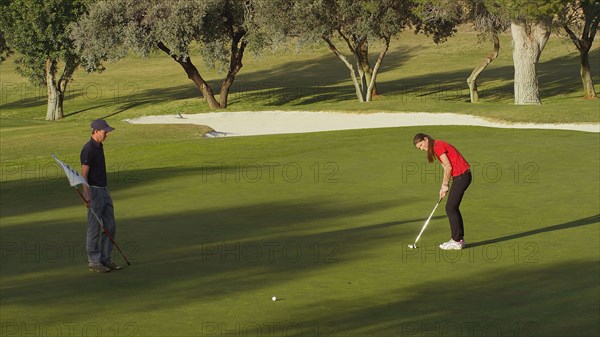 Caucasian couple putting on golf course