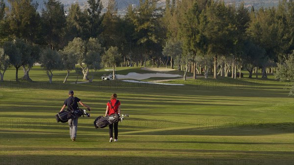 Caucasian couple carrying golf bags on course