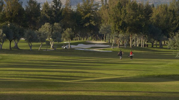 Caucasian couple carrying golf bags on course