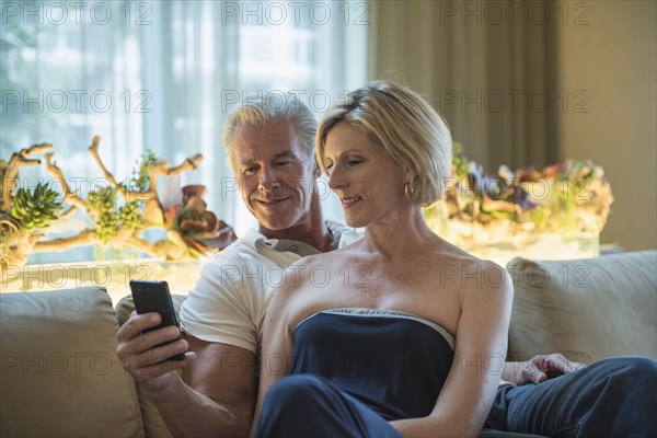 Caucasian couple using cell phone in hotel lobby