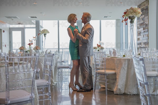 Caucasian couple dancing in empty restaurant