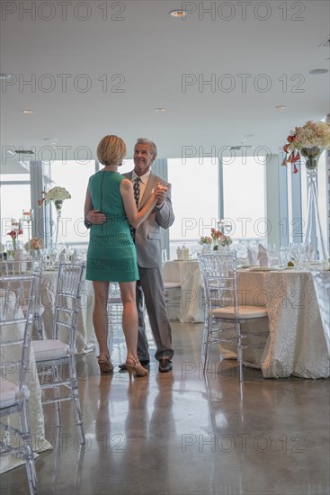 Caucasian couple dancing in empty restaurant