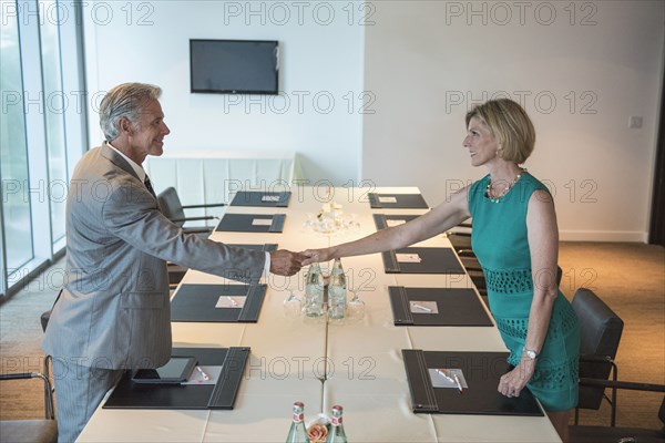 Caucasian business people shaking hands in conference room