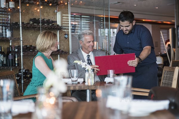 Waiter assisting couple with menu in restaurant