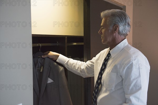 Caucasian businessman selecting suit from closet