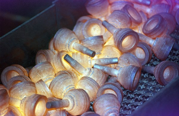 Glowing metal manufactured pieces on conveyor belt