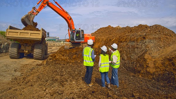 Workers watching digger machinery in field