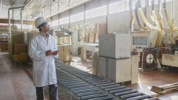 Hispanic worker checking production line in factory