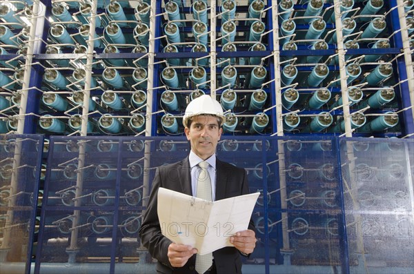 Hispanic businessman smiling in power plant