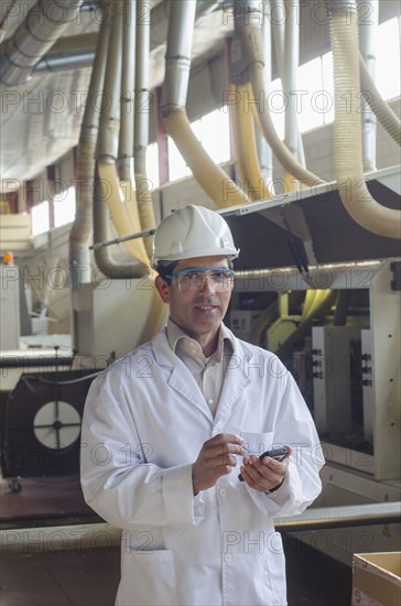 Hispanic technician using cell phone factory