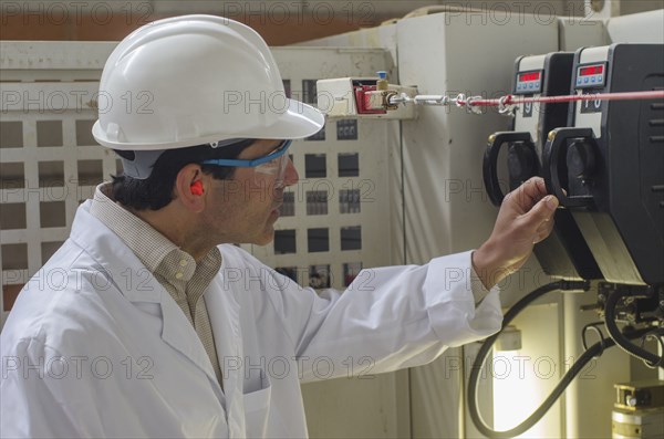 Hispanic technician checking machinery in factory