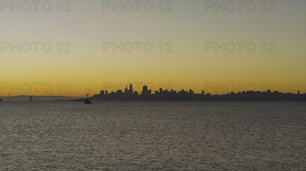 Silhouette of urban waterfront skyline at sunset