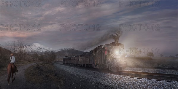 Woman on horse watching train in remote landscape