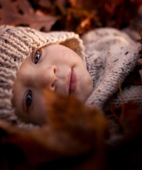 Close up of baby boy laying in autumn leaves