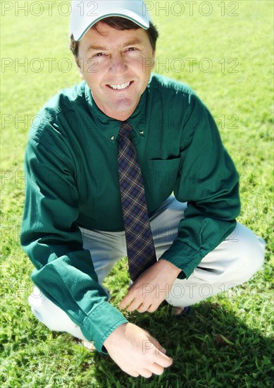 Businessman crouching on grass lawn