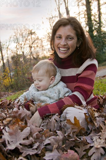 Mother and son sitting in autumn leaves