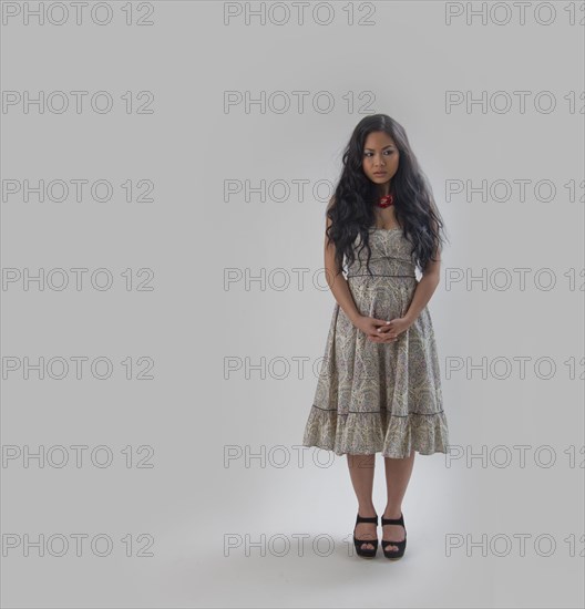 Asian woman standing with hands clasped