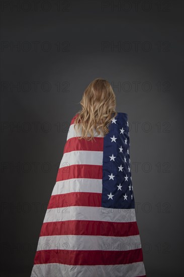 Mixed race woman wrapped in American flag