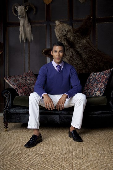 Man sitting on loveseat under trophy animals