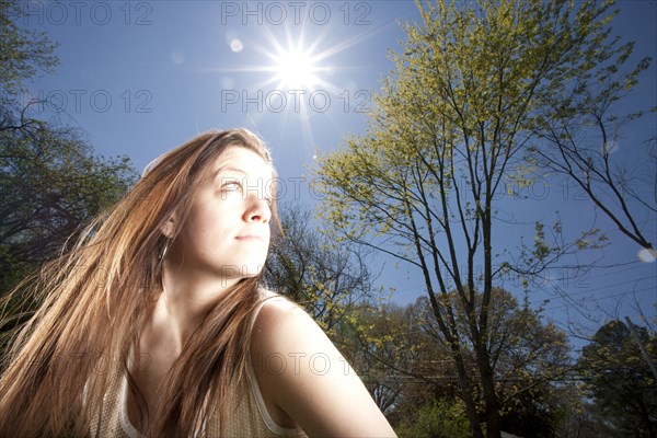 Caucasian woman looking away in sunny forest