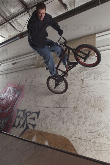 Man riding bicycle on wall indoors