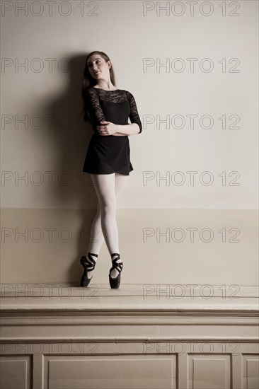 Caucasian ballet dancer balancing on mantle on wall