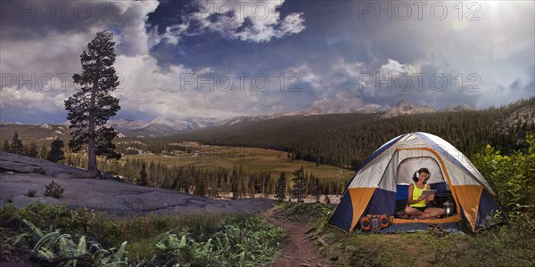 Hispanic woman listening to digital tablet in camping tent