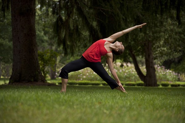 Caucasian woman doing yoga stretching in field